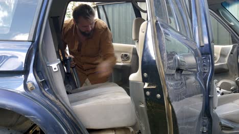 hombre aspirando el interior del vehículo de limpieza suv después de un viaje por carretera