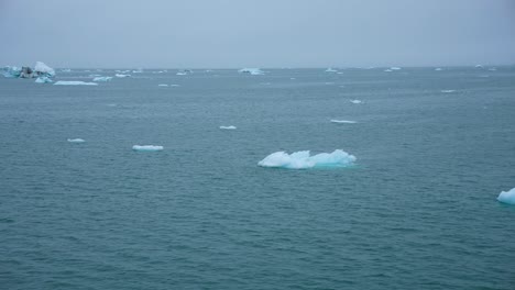 pieces of ice floating in cold arctic sea water, sailing pov