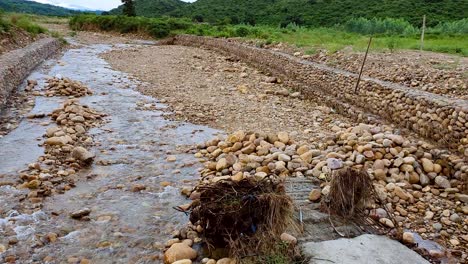 dry rocky creek amidst green mountains, flowing with water during rainy season