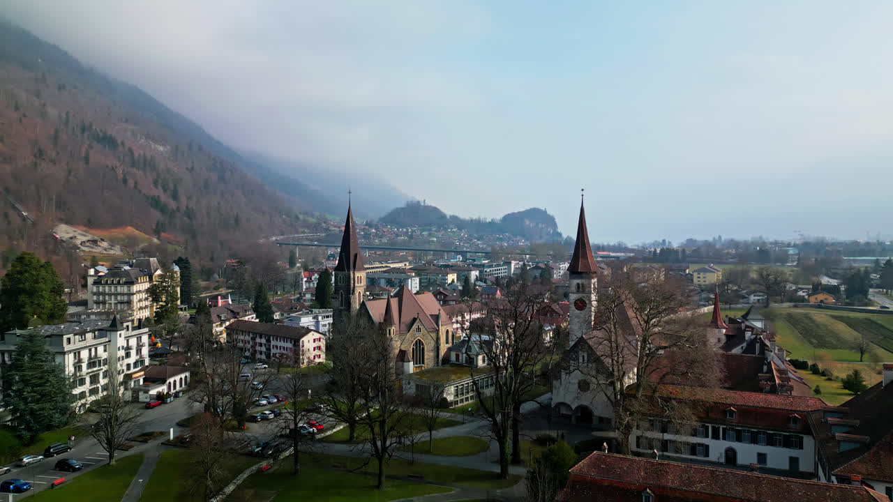 el retiro aéreo deja catedrales y capillas con vistas a interlaken, suiza. las casas se extienden en la distancia.
