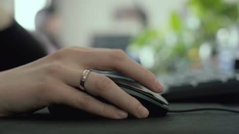 Hand-using-a-mouse-on-a-desk-in-an-office,-selective-focus-scrolling-and-clicking