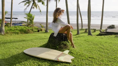 woman sitting next to surfboard