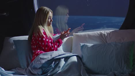 woman in pajamas using smartphone in space