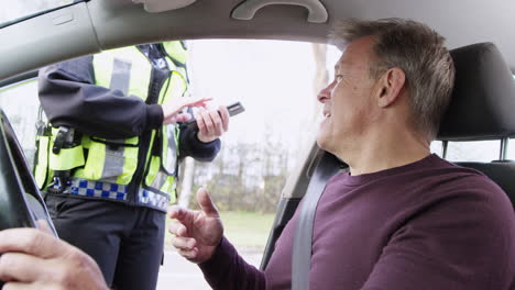 male driver being stopped by female traffic police officer with digital tablet for driving offence