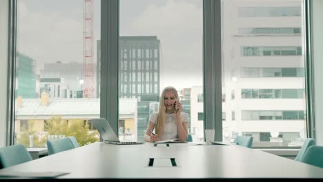 businesswoman waving with hand while speaking on phone. stylish businesswoman having phone call while sitting at table in conference hall and waving with hand greeting colleague