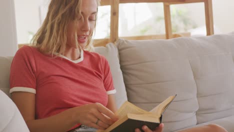 Schöne-Frau-Liest-Bücher,-Während-Sie-Auf-Der-Couch-Sitzt