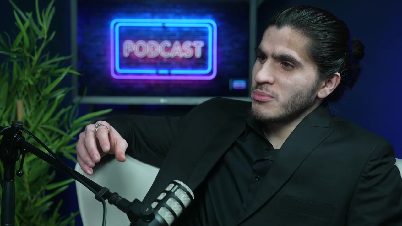 Man in dark studio speaking expressively into microphone during podcast recording