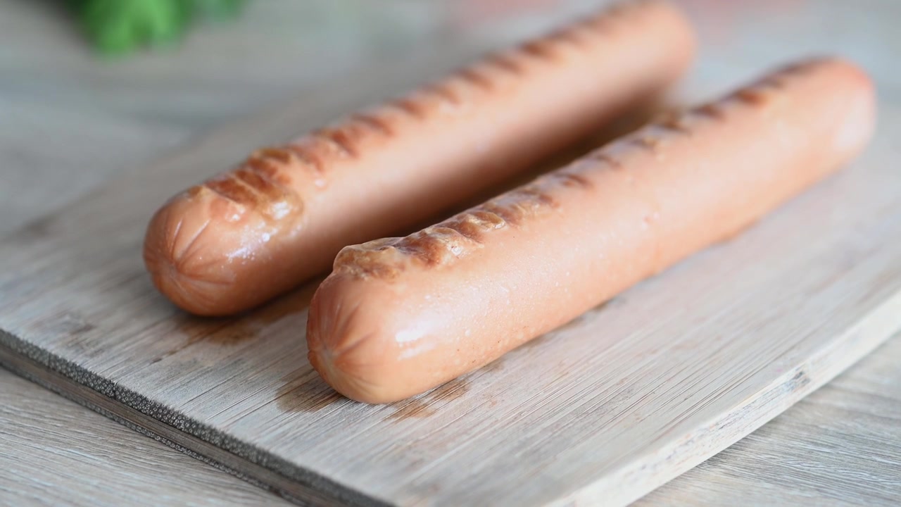Två grillade korvar på en träskärbräda