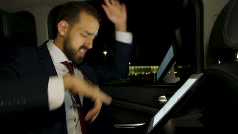 excitado hombre de negocios en traje bailando en el asiento trasero de su limusina