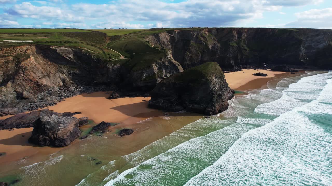 Bedruthan Steps Along the Cornish Coastal Path with Views of Beach and Ocean Waves from an Aerial Drone