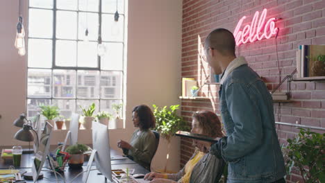 stylish young businesman team leader enjoying management career checking colleagues working using tablet computer confident manager walking in diverse office workplace