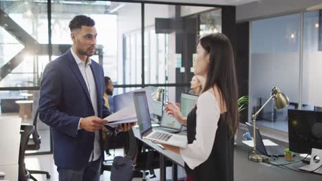 dos empresarios diversos discutiendo juntos usando una computadora portátil y de pie en la mesa