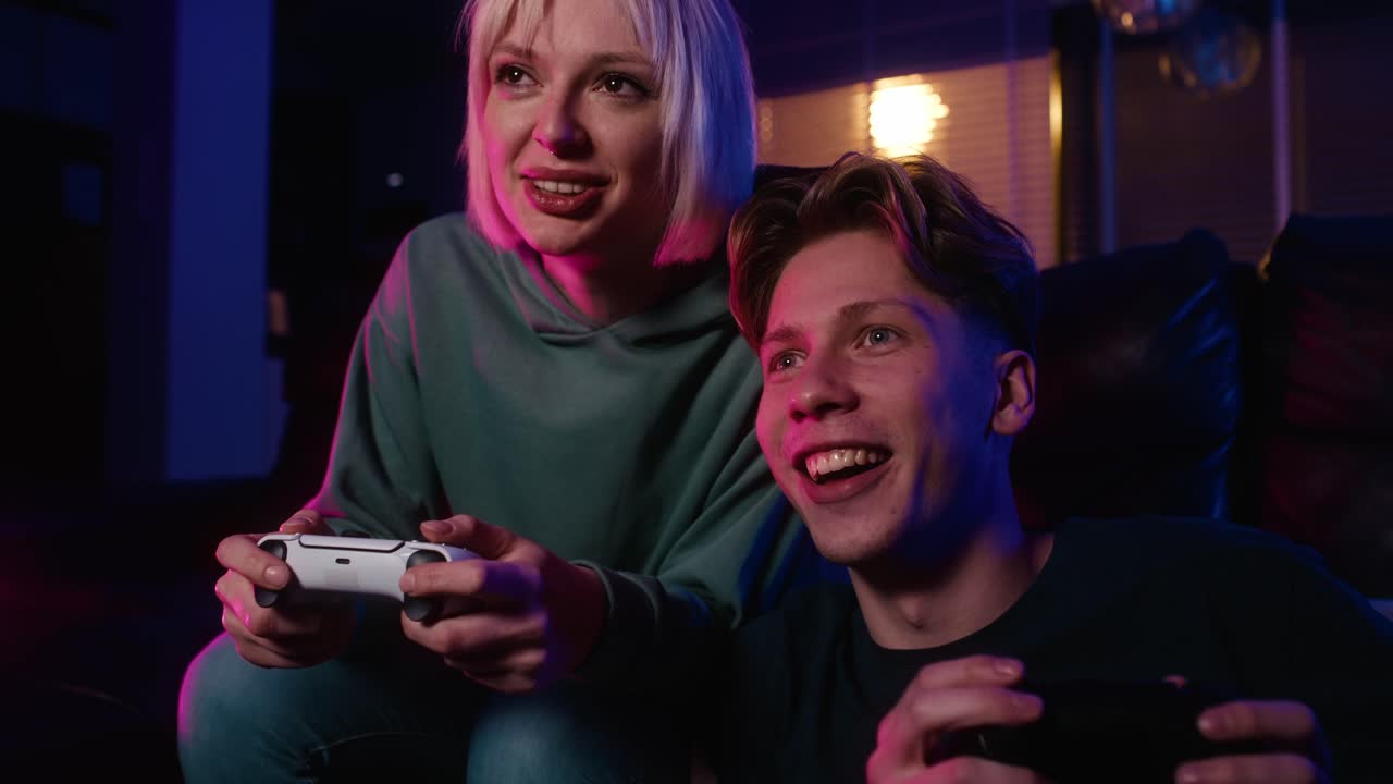 젊은 백인 커플이 게임 패드와 함께 비디오 게임을 하고 있습니다.