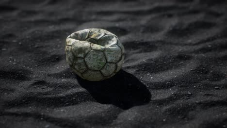 vieja pelota de fútbol en la arena negra