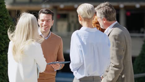 group of happy business professionals discussing outdoors with a tablet