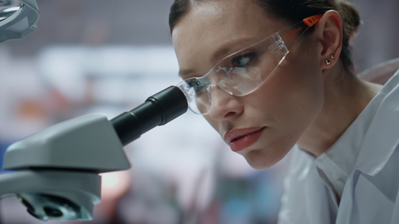 bioquímico de primer plano mirando el microscopio explorando la muestra en el laboratorio de la clínica.