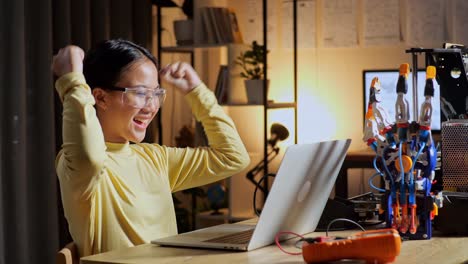 teen asian girl celebrating succeed working about a cyborg hand on a laptop at home