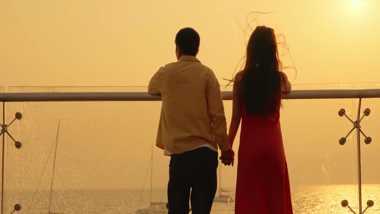 A romantic couple watches the sunset over the ocean from a viewpoint