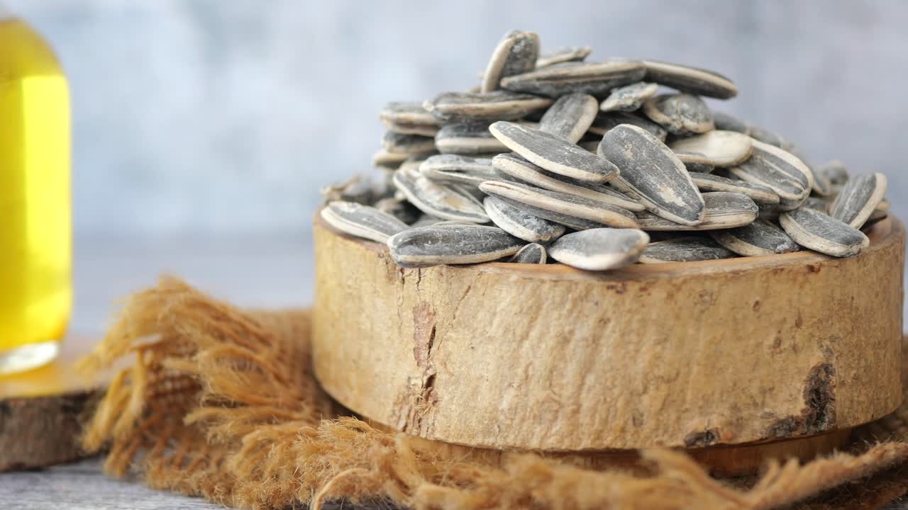 A wooden bowl filled with sunflower seeds and a bottle of oil