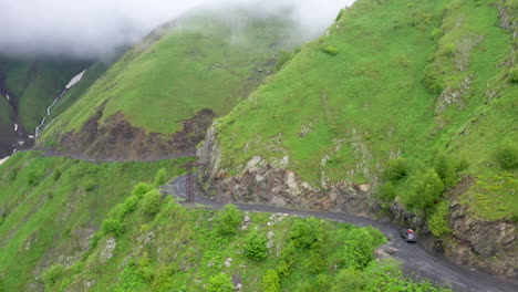 desecending drone shot of a vehicle driving on the road to tusheti on the abano pass in georgia