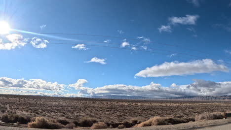 driving through the mojave desert on a highway in southern california by utility poles and rugged terrain - passenger window point of view hyper lapse