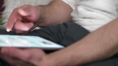 man-with-a-tablet-in-his-lap-browsing-internet,-slide-L-to-R