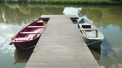 small boats at wooden dock on lakeside with reflections