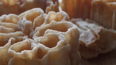zoom in on a flor frita, a spanish sweet fried pastry with flower shape and sugar coating over wooden background