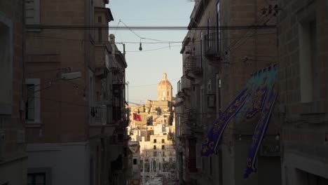 narrow street with flags in malta, overlooking one of the three cities