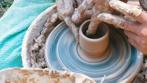 man and woman potter's hands work with clay on a potter's wheel