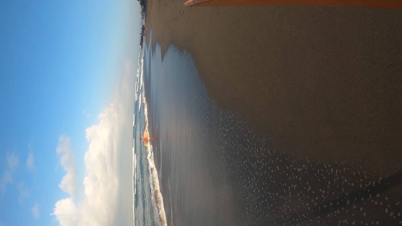 persona que lleva tabla de surf y camina en la playa de arena en bali, vista vertical pov