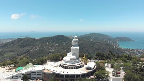 profile view of phuket big buddha overtaking the exotic urban thai landscape - aerial fly-over overtake shot