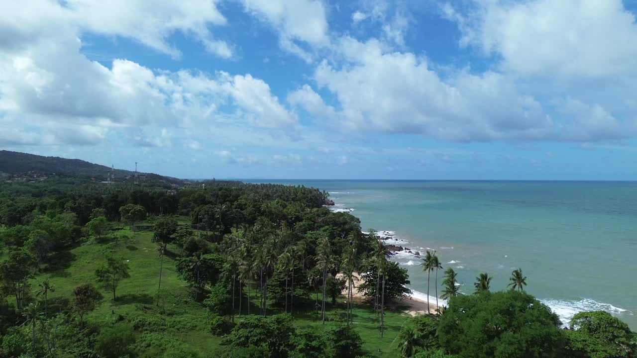 Aerial drone Aerial drone footage of Koh Lanta, Thailand, featuring traditional longtail boats anchored near a tropical coastline with palm trees, rocky shore and remote beaches in the background