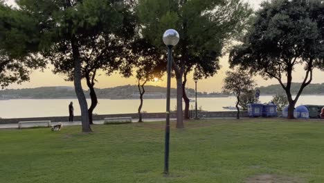 puesta de sol en vouliagmeni sobre el área de césped con el mar en el fondo