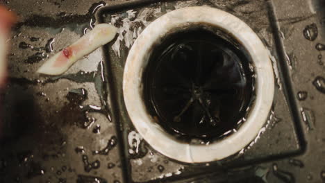 man throwing food waste into the garbage disposal in the kitchen sink. top view