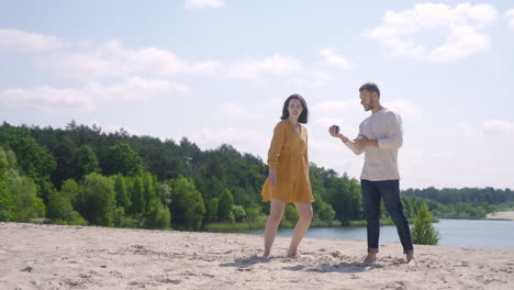 two caucasian young man and woman friends playing petanque on the beach on a sunny day