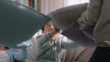 happy asian family having pillow fight mother and father enjoying playing with children at home having fun together on weekend 4k footage