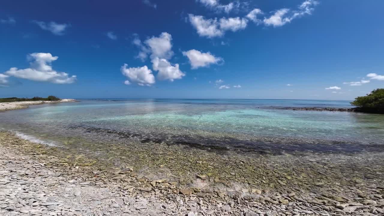 día brillante en la playa de coral, los rocas con aguas claras de color turquesa y nubes esponjosas