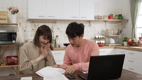 happy asian young couple planning family finance together at home. the man smiling with clenched fist and clapping hand with his wife cheering for successful investment