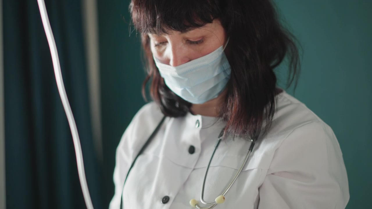 Allestimento per infusione medica. Professionista sanitario stabilisce l'accesso endovenoso durante una visita domiciliare. Medico assembla con cura la linea endovenosa per il trattamento del paziente nell'ambiente di assistenza sanitaria domiciliare