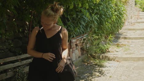 Young-female-tourist-pauses-exploring-to-rest-in-shade-on-hot-sunny-day