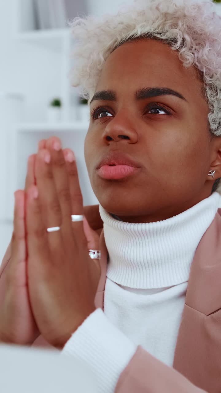 Young woman meditates with hands clasped in modern office thoughtful expression