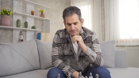 un primer plano de un hombre solitario, reflexivo e infeliz jugando al ajedrez solo.