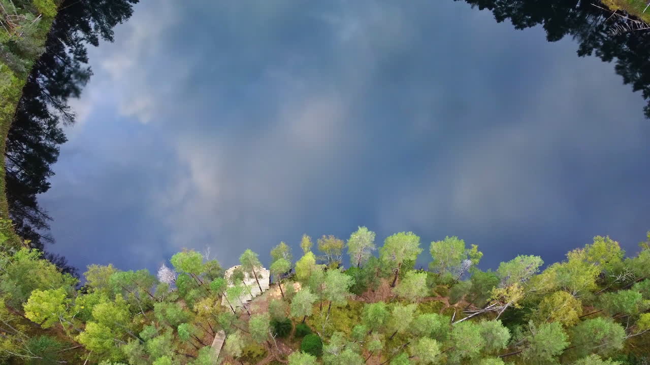 Top view of forested lake with clear sky reflection in Certoks-Velnezers