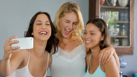 Smiling-friends-taking-selfie-in-kitchen