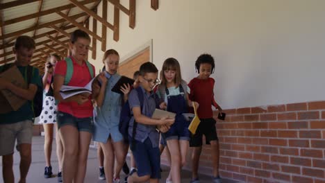 grupo de niños con libros caminando en el pasillo de la escuela