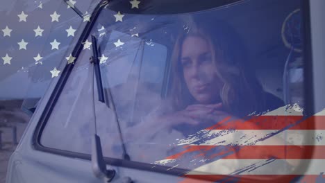 Animación-De-La-Bandera-Estadounidense-Dibujada-Sobre-Una-Mujer-Caucásica-Mirando-Por-La-Ventana-Del-Auto-En-La-Playa