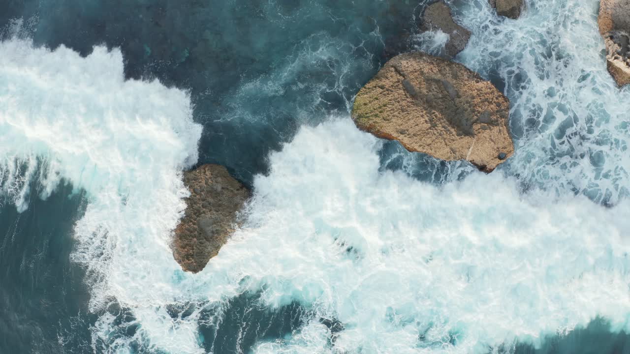 Splendida vista aerea dall'alto di onde oceaniche che si infrangono contro grandi rocce sulla costa