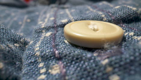 close-up, rack focus on a button of a blue, denim shirt