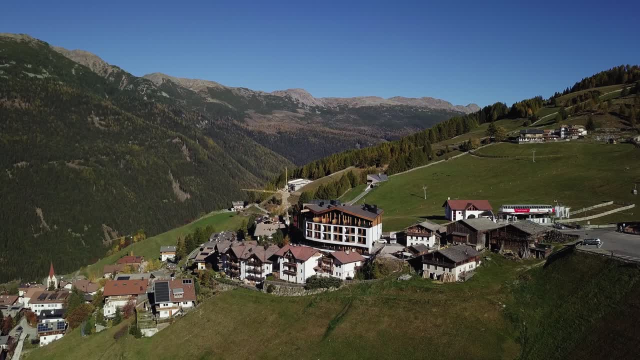 Mountain hotel on a hill with houses and road and valley orbit around